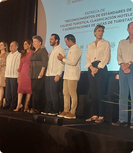 Fundadora de COINCA recibiendo reconocimiento en escenario junto a colaboradores.